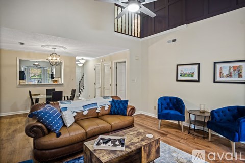 A living room with a brown leather couch and blue chairs.