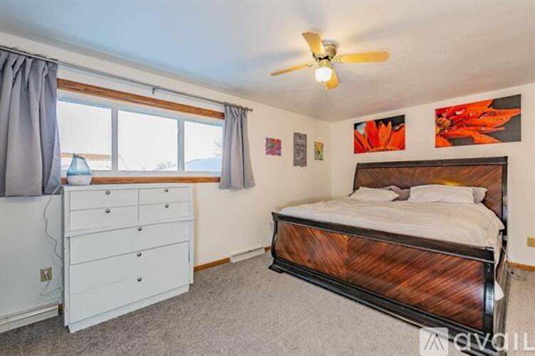 A bedroom with a bed, dresser, and ceiling fan.
