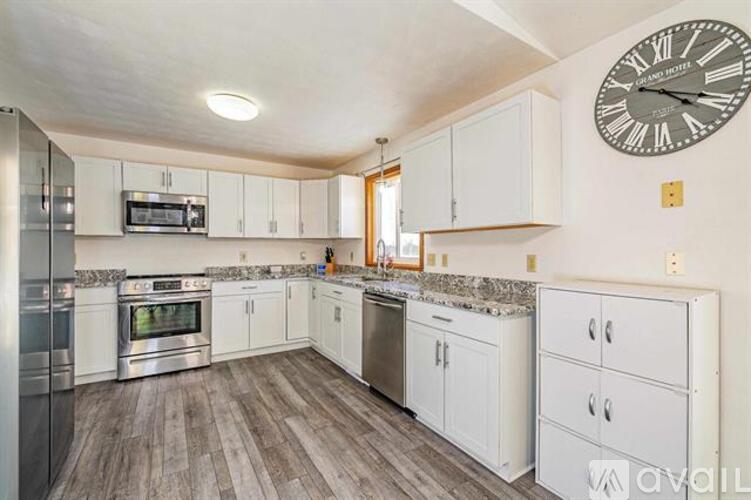 A kitchen with white cabinets and a wooden floor.