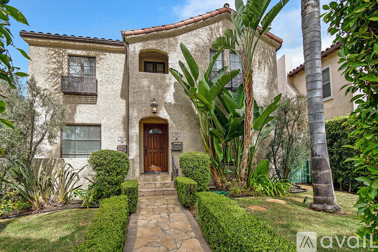 A house with a brown door is surrounded by green plants.