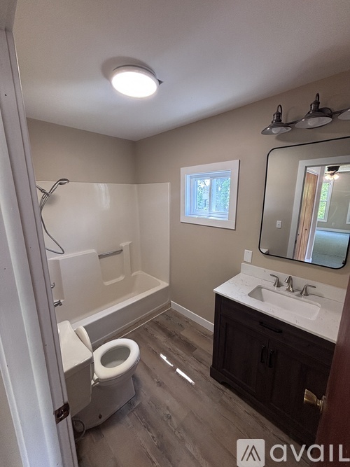 A bathroom with a toilet, sink, and mirror.