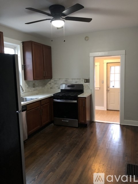 A kitchen with a black refrigerator and wooden cabinets.