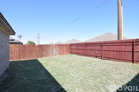 A backyard with a red fence and green grass.