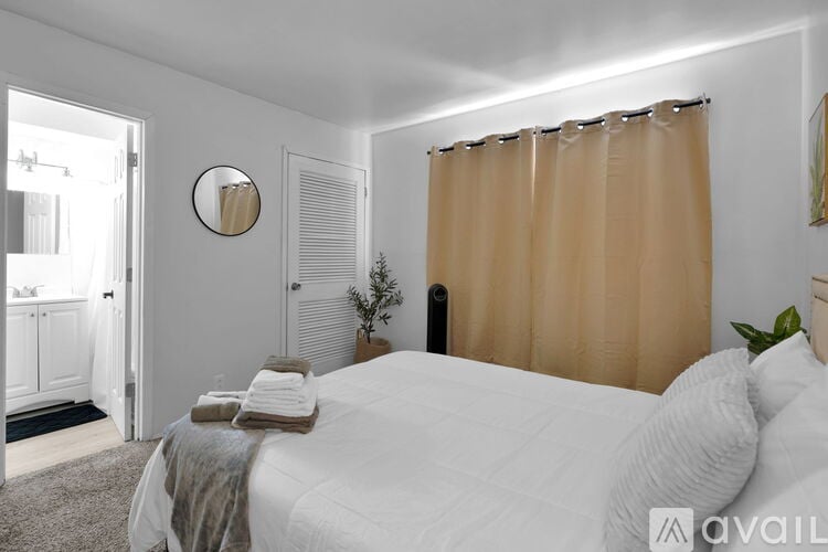 A bedroom with a bed, pillows, a mirror, and a plant.