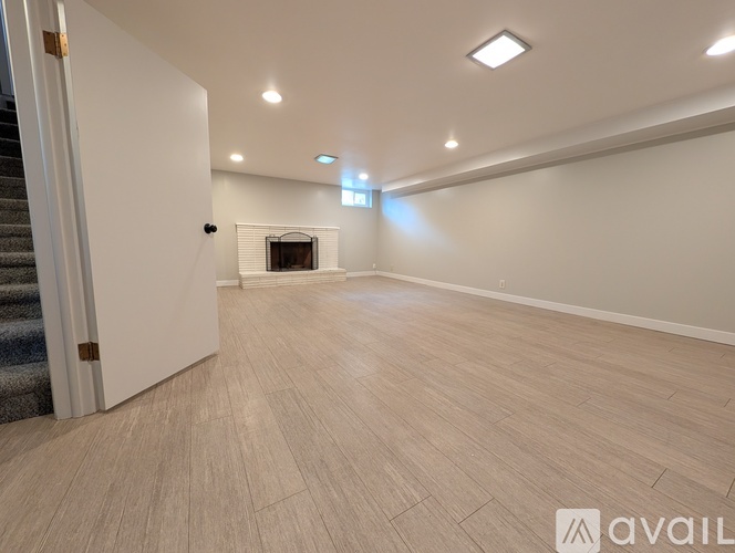 A spacious room with a fireplace and wooden flooring.