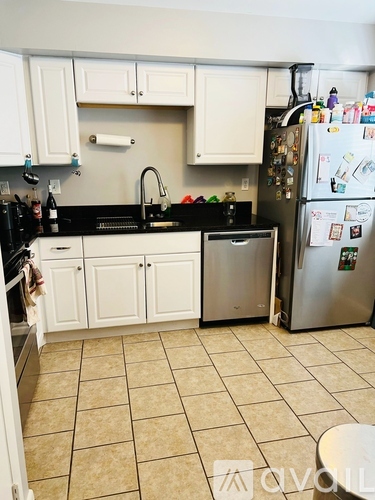 A kitchen with white cabinets and a black counter top.
