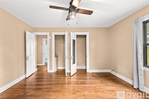 A kitchen with white cabinets and brown flooring.