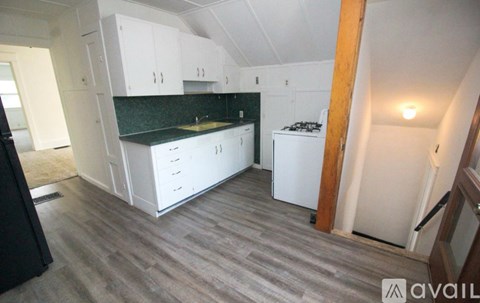 A kitchen with white cabinets and a green backsplash.