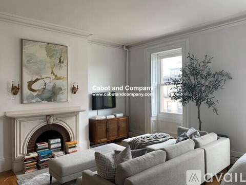 A living room with a fireplace, a grey sofa, and a painting on the wall.