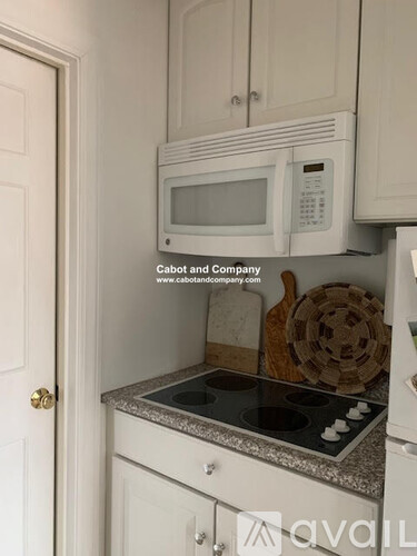 A white microwave is mounted above a white stove in a kitchen.
