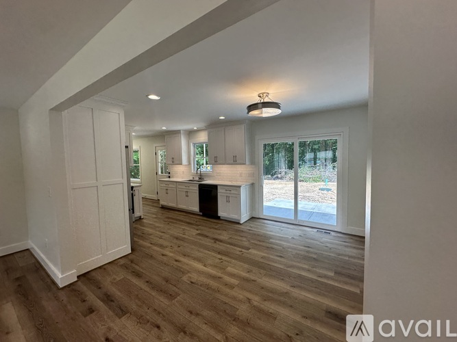 A spacious kitchen with white cabinets and a wooden floor.