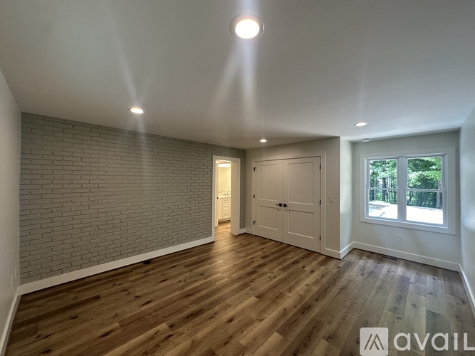 A room with wooden flooring and a brick wall.