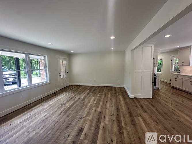 A spacious room with wooden flooring and white walls.