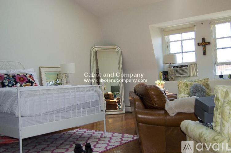 A bedroom with a white bed and a brown leather chair.