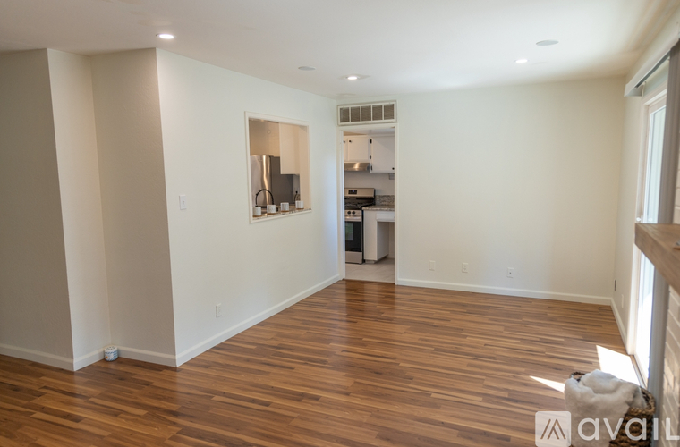 A spacious room with wooden flooring and a mirror on the wall.