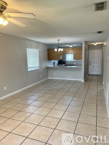 A spacious room with tiled flooring and a ceiling fan.