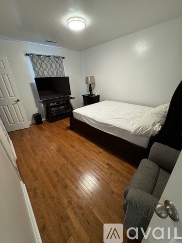 A bedroom with a bed, a dresser, and a television.