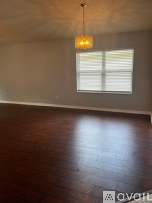 A room with wooden floors and a window with blinds.