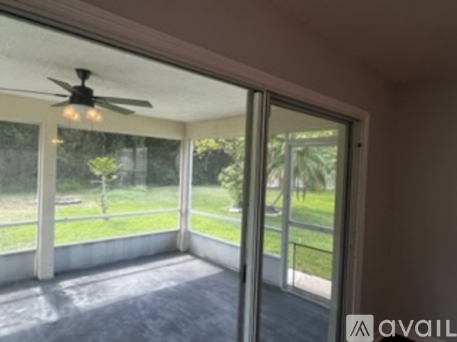 A room with a ceiling fan and sliding glass doors.