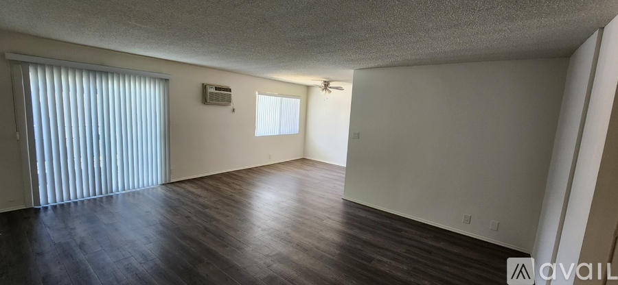 A spacious room with wooden floors and a sliding door.