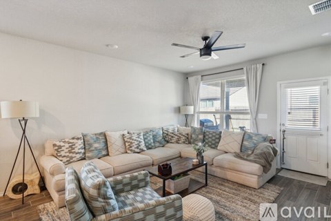 A living room with a couch, chair, and a table with a vase of flowers on it.
