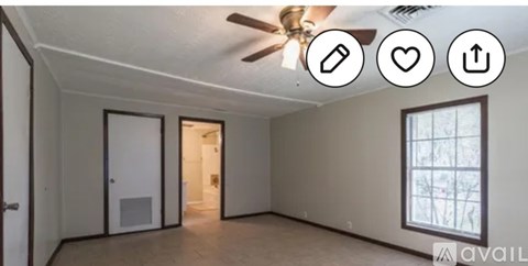 A room with a ceiling fan and a window with a view of trees outside.