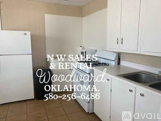 A kitchen with a white fridge and cabinets is for sale or rent in Woodward, Oklahoma.