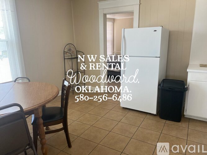 A room with a table and chairs and a fridge in it.