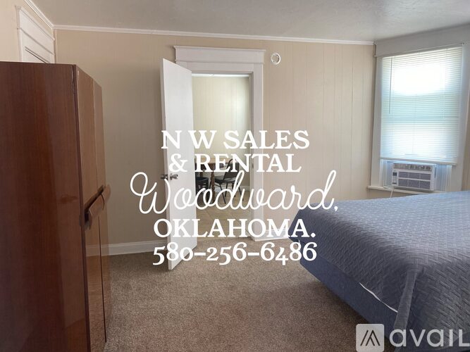 A bedroom with a bed, dresser, and window with blinds, advertising NW Sales & Rental Woodward, Oklahoma.