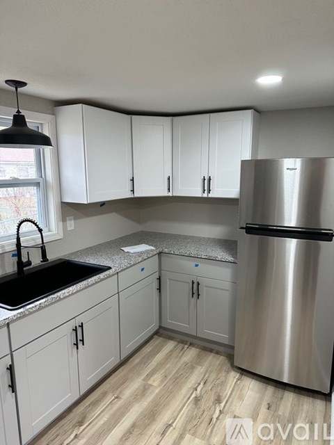A kitchen with white cabinets and a stainless steel refrigerator.