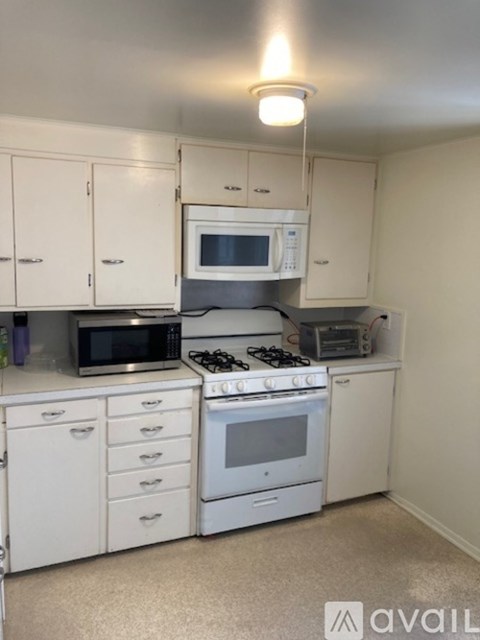 A kitchen with white cabinets and appliances.