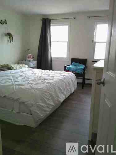 A bedroom with a bed, chair, and window.