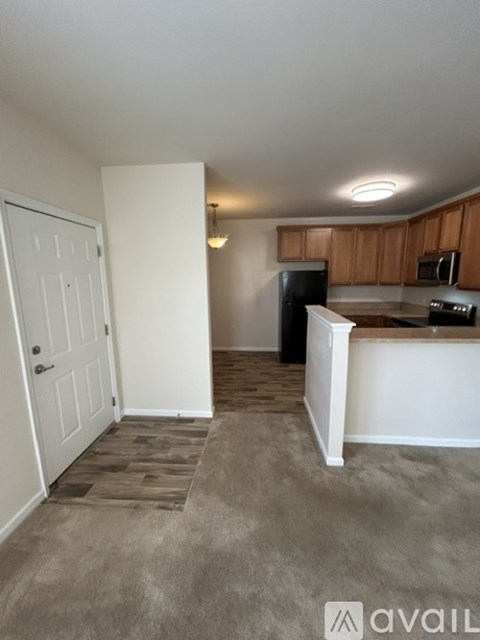A kitchen area with wooden cabinets and a black fridge.