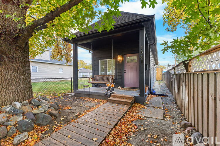 A small house with a porch surrounded by a fence and trees.