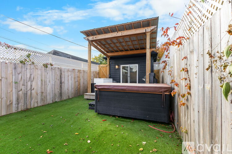 A hot tub is in a backyard surrounded by a wooden fence.