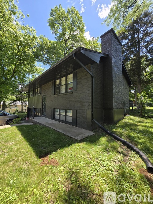 A house with a chimney and a porch is surrounded by greenery.