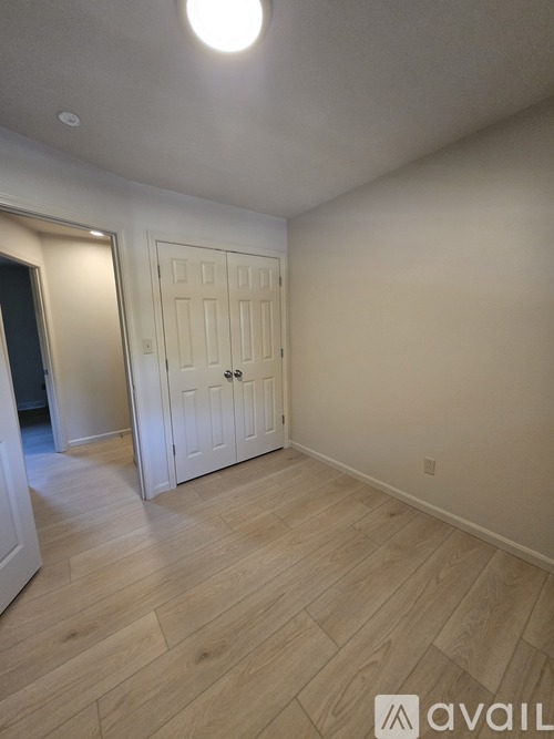 A room with a white door and wooden flooring.