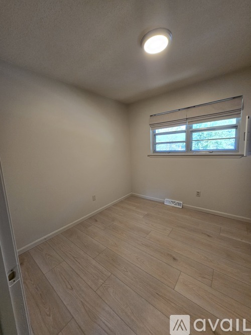 A room with wooden flooring and a window with blinds.