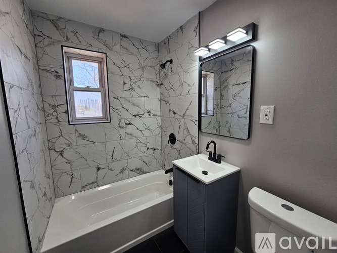 A bathroom with a marble wall and a white bathtub.