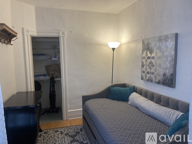 A bedroom with a bed, a desk, and a painting on the wall.