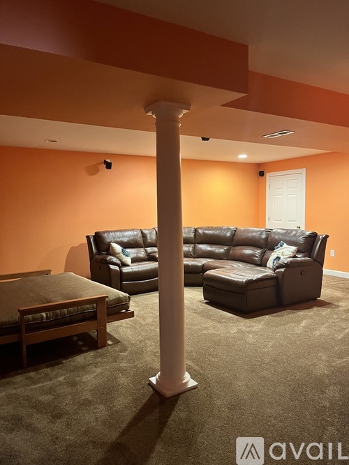 A living room with a brown couch and a white column.