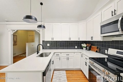 A kitchen with white cabinets and black appliances.
