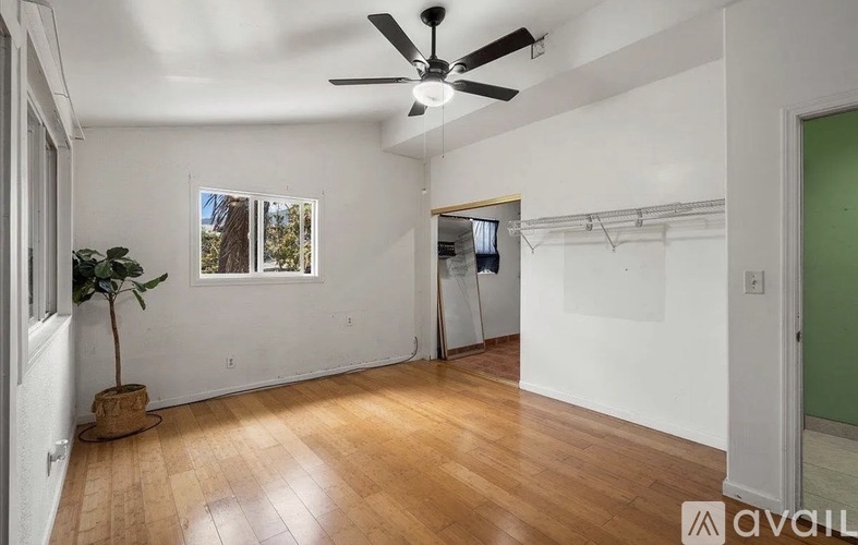 A room with a ceiling fan and wooden flooring.