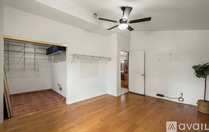 A room with a ceiling fan and wooden floors.