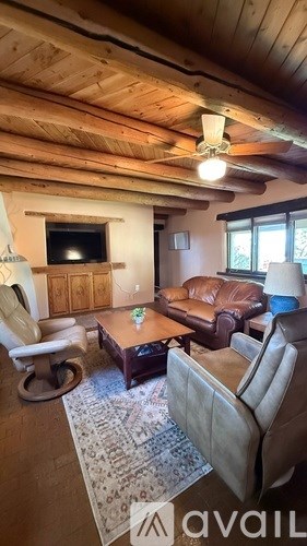 A living room with a brown leather couch and a wooden ceiling.