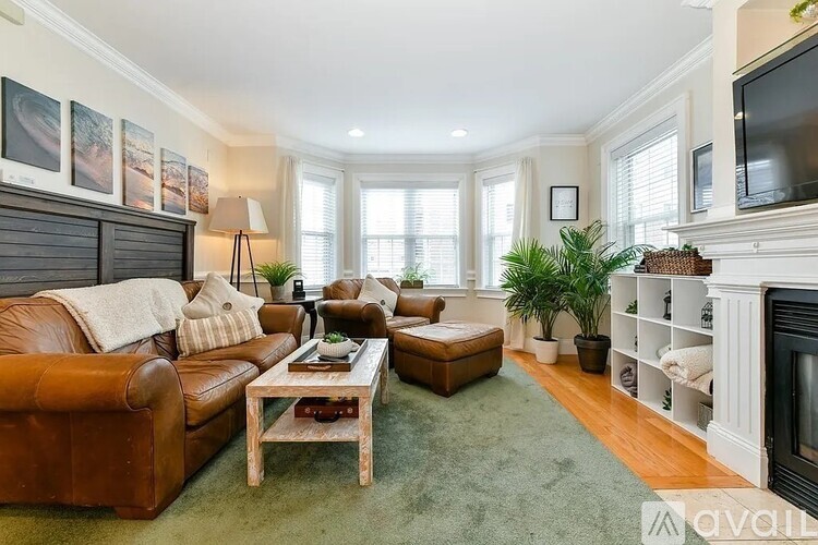 A living room with a brown leather couch, a coffee table, and a fireplace.