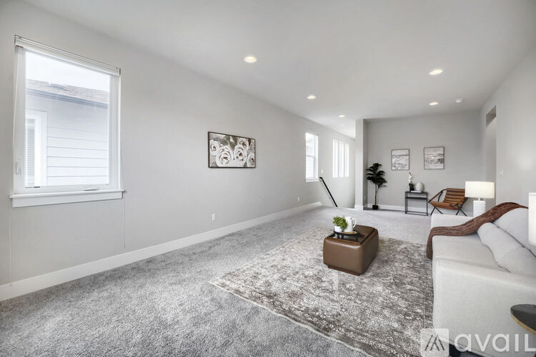 A spacious living room with a grey carpet and a white sofa.