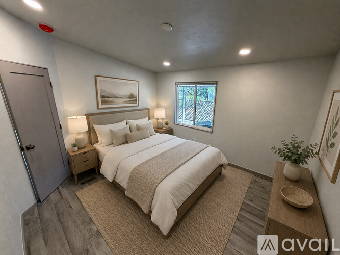 A bedroom with a large bed, a nightstand with a lamp, and a framed picture on the wall.