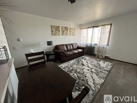 A living room with a brown couch, a wooden table, and a rug.