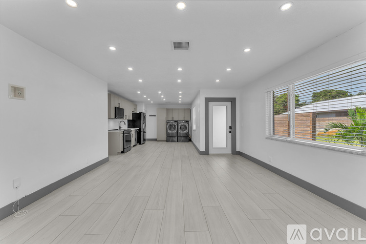 A spacious room with wooden flooring and a row of windows on the right side.
